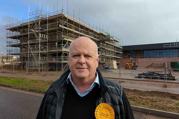 Paul Arnott standing in front of a block of flats under construction