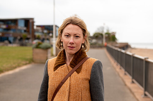 Charlotte FitzGerald standing on Exmouth seafront with a concerned expression