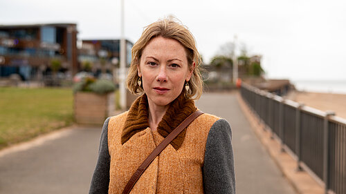 Charlotte FitzGerald standing on Exmouth seafront with a concerned expression