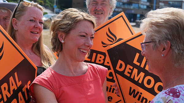 Charlotte surrounded by Lib Dem supporters carrying orange stakeboards